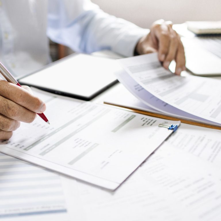 Asian businessman reviewing document report at office working with laptop, professional lawyer reading and checking financial documents or insurance contract before sign, Close-up shot