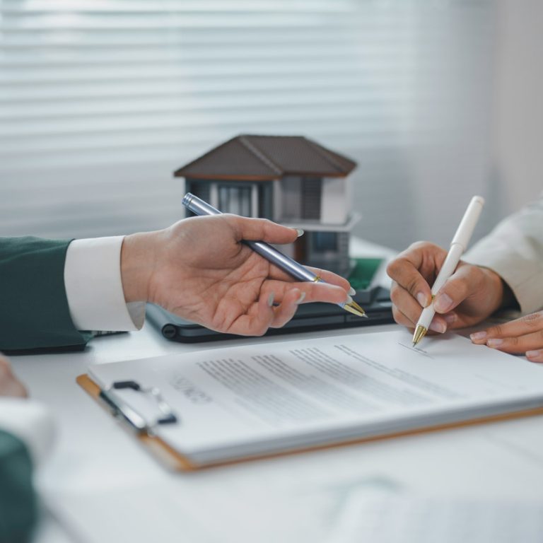 Client signing a contract for a new house, real estate agent pointing at signature place